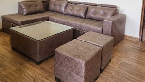 Uma sala de estar moderna com um sofá seccional, uma mesa de centro de vidro e um ventilador de teto.