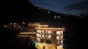 Um edifício de vários andares com varandas e fachada iluminada à noite.
