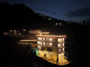 Un edificio de varios pisos con balcones e iluminación exterior en la noche.