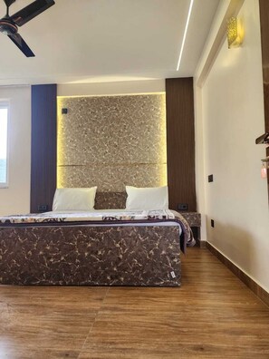 A bedroom with a bed, a ceiling fan, a wall-mounted light fixture, and a nightstand. - Mountain Stories Mukteshwar  (Dhari)