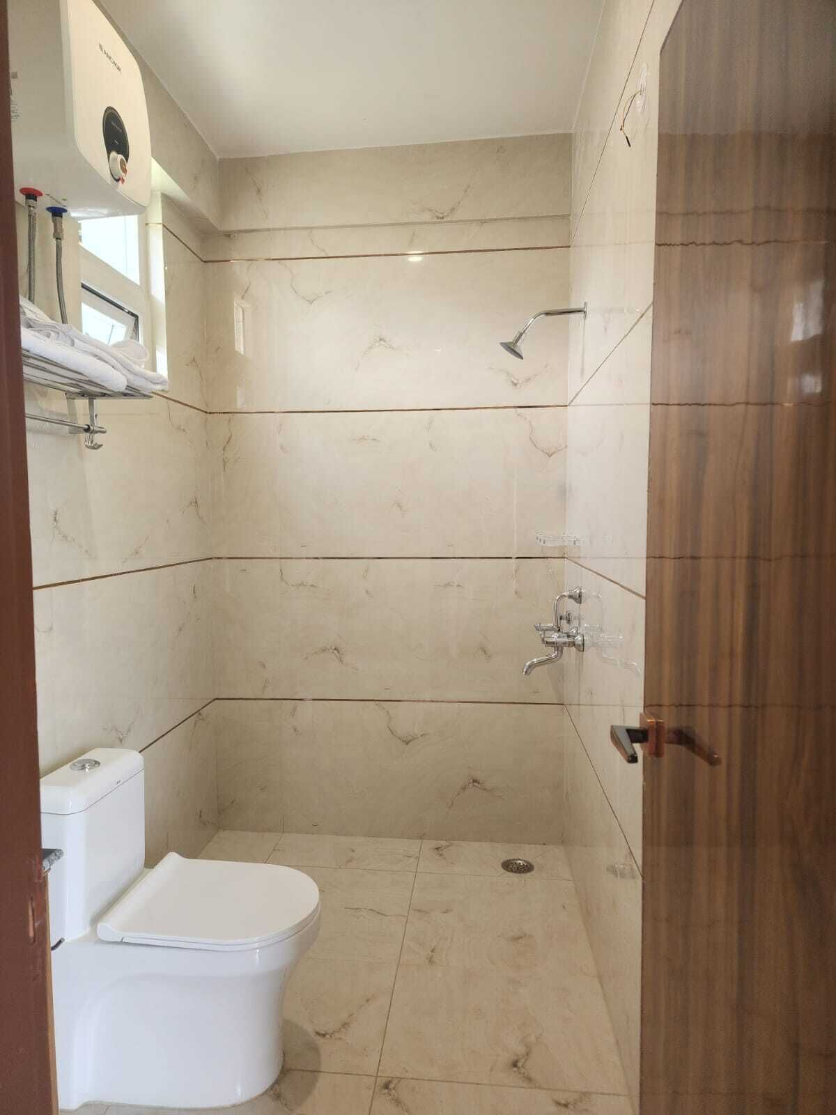 Un baño con inodoro, ducha y puerta de madera.