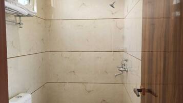 Un baño con inodoro, ducha y puerta de madera.