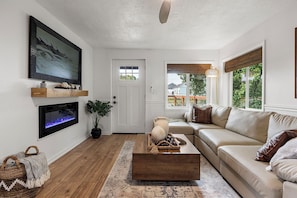 Ein Wohnzimmer mit Sofa, Couchtisch, Fernseher und Kamin.