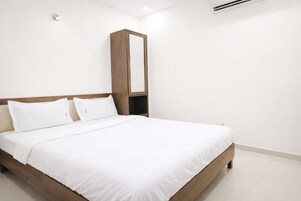A hotel room with a single bed, a wooden headboard, and a large mirror.