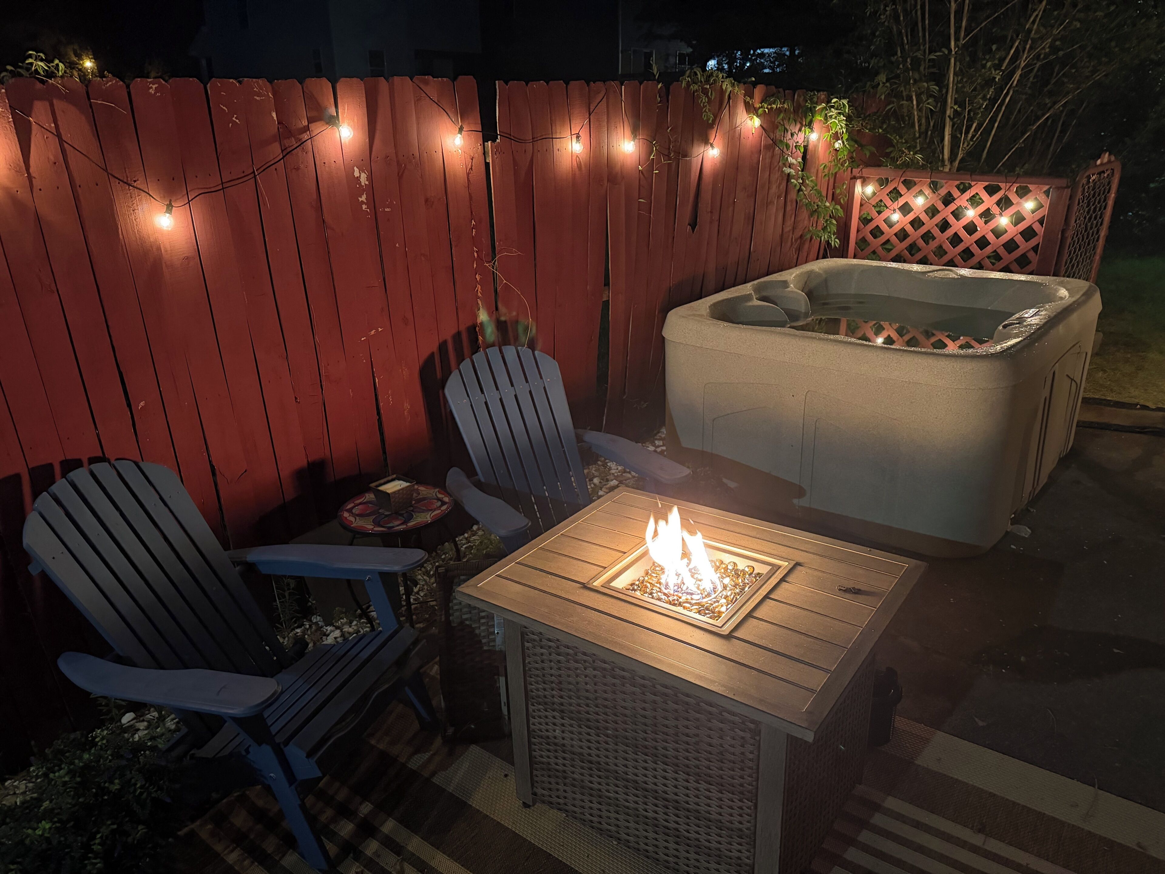 Une terrasse extérieure avec un foyer, deux fauteuils Adirondack et un jacuzzi.