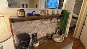 Eine Küche mit einer Holzausstattung, einer Kaffeemaschine und einem Fernseher an der Wand.