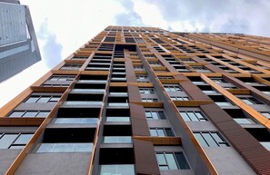 Un immeuble de grande hauteur doté d’une architecture moderne, caractérisé par une façade à motifs et une série de fenêtres disposées en réseau.