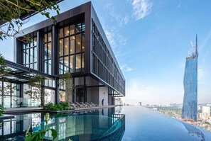 Un bâtiment moderne doté d’une piscine à débordement sur le toit et offrant une vue sur un gratte-ciel imposant.