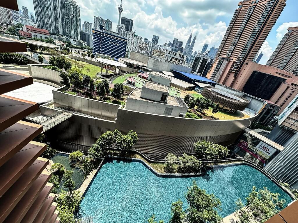 Un bâtiment moderne doté d’une piscine sur le toit et entouré de verdure.