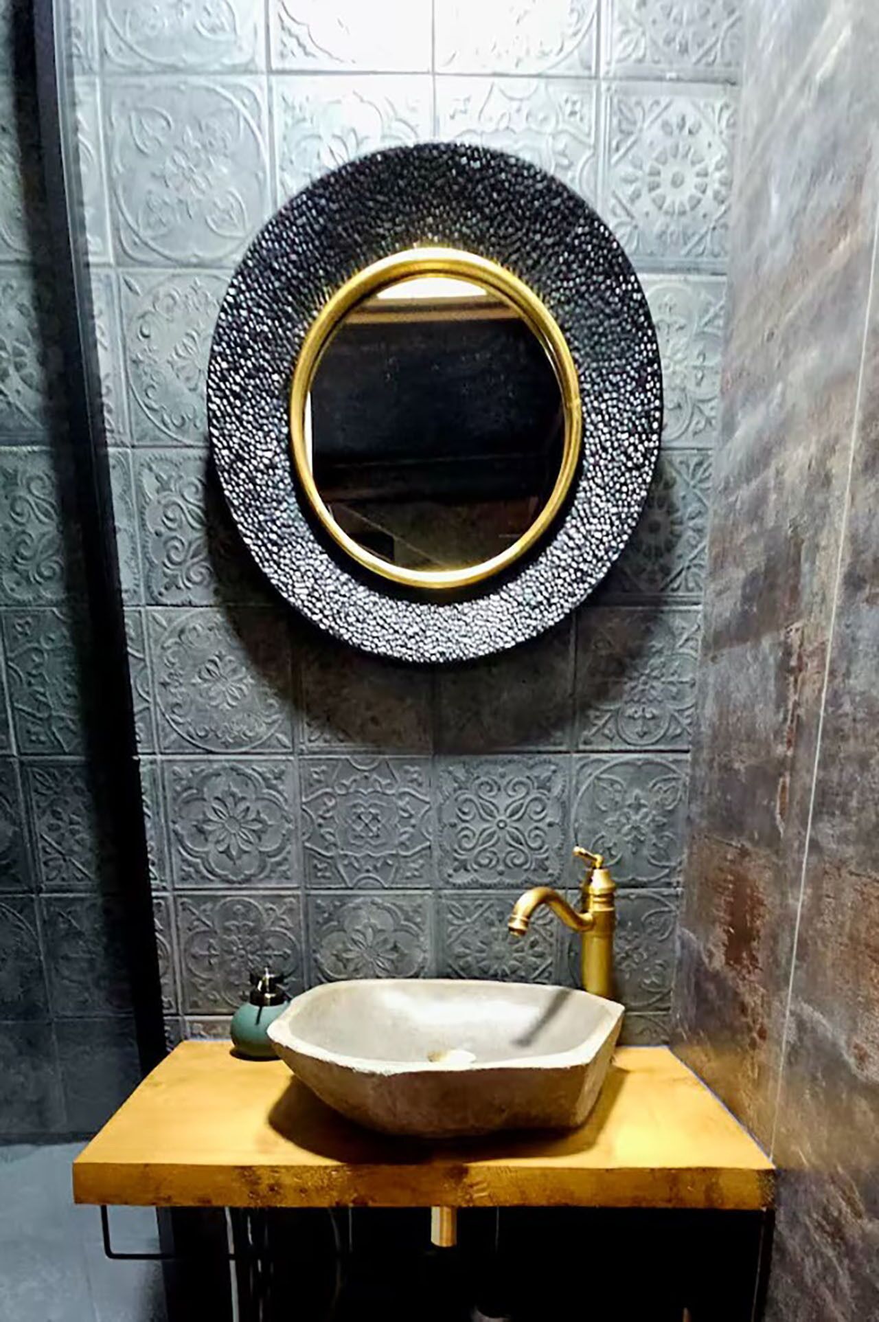 A bathroom with a round mirror, a sink, and a faucet.