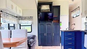 Un intérieur de camping-car compact comprenant un coin repas, une kitchenette et un petit espace salon.