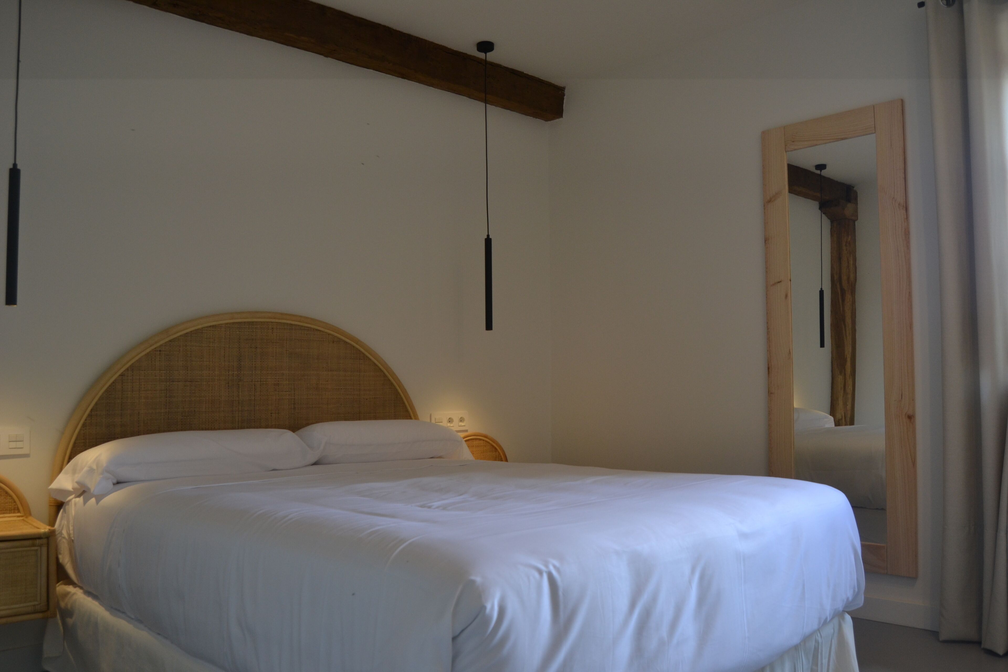 Una camera da letto con un letto grande, una testiera in legno, comodini e uno specchio.