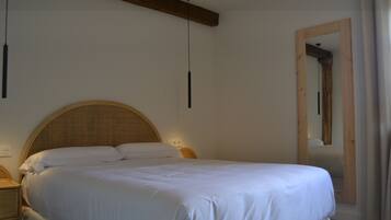 Una camera da letto con un letto grande, una testiera in legno, comodini e uno specchio.