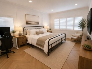 Une chambre à coucher moderne, comprenant un lit, des tables de chevet, un bureau, une chaise et un téléviseur.