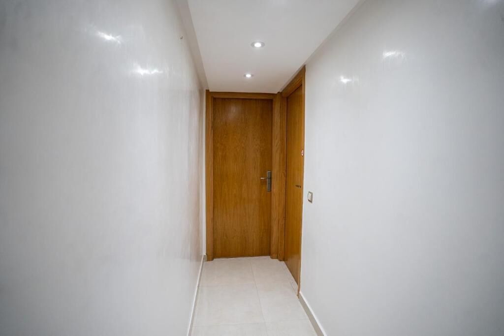 A narrow hallway with white walls and a wooden door at the end.