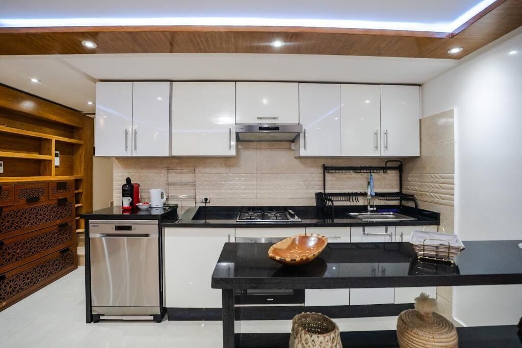 Una cocina moderna con armarios blancos, encimera negra y estufa integrada.