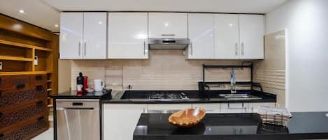 Una cocina moderna con armarios blancos, encimera negra y estufa integrada.