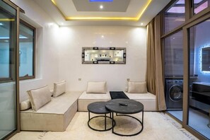 A modern living room with a sectional sofa, two round tables, and a large mirror on the wall. - Cozy Sh'Amira Duplex Apartment in Semlalia (Marrakech)