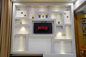 A modern entertainment wall with a large flat-screen TV displaying 'NETFLIX' and various decorative items. - Cozy Sh'Amira Duplex Apartment in Semlalia (Marrakech)