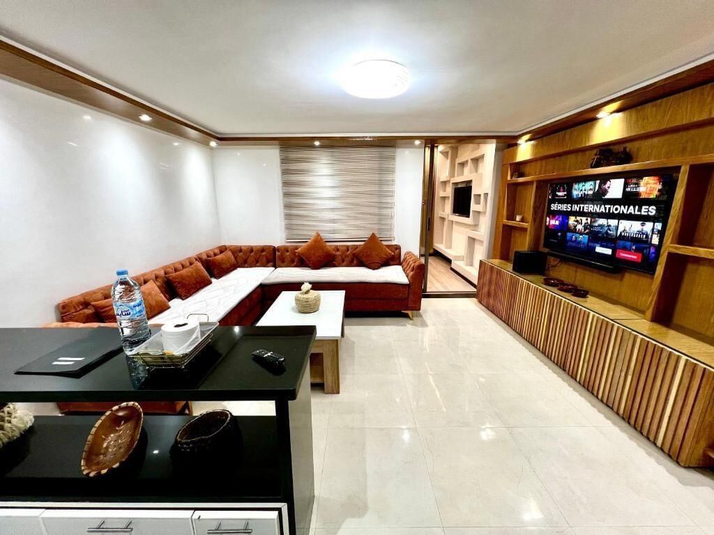Un salon moderne avec un canapé d’angle, un téléviseur à écran plat et un meuble de rangement en bois.