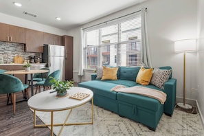 A modern living room with a teal sofa, a round coffee table, and a dining area with a small table and chairs. - Midtown Dallas Escape | 1BR 1BA Suite | Pool | Free Parking (Dallas)