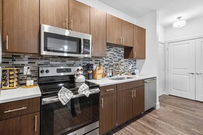 Una cocina moderna con electrodomésticos de acero inoxidable, gabinetes de madera y un salpicadero de azulejos.