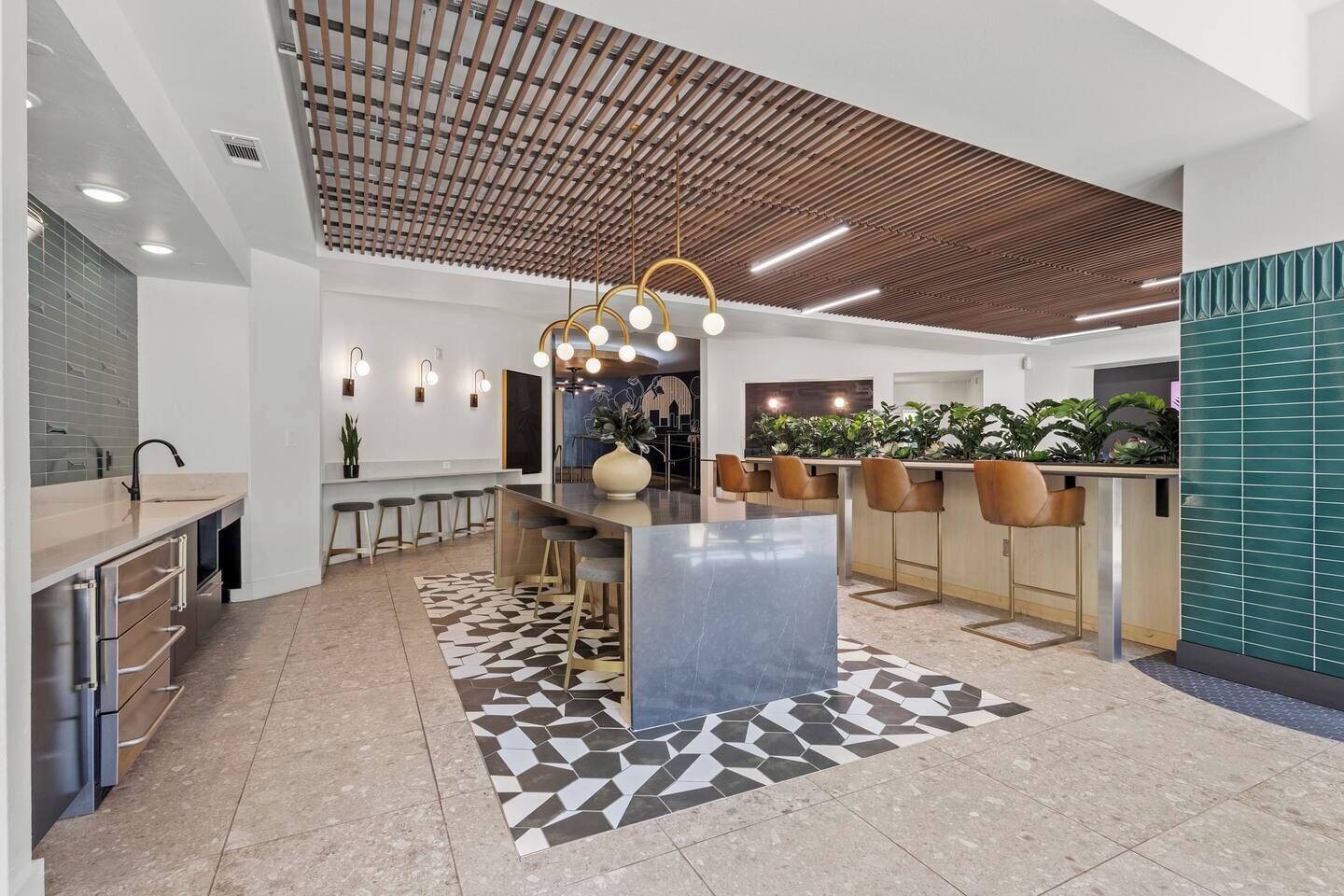 Une cuisine moderne dotée d’un îlot central, de tabourets de bar et de luminaires suspendus.
