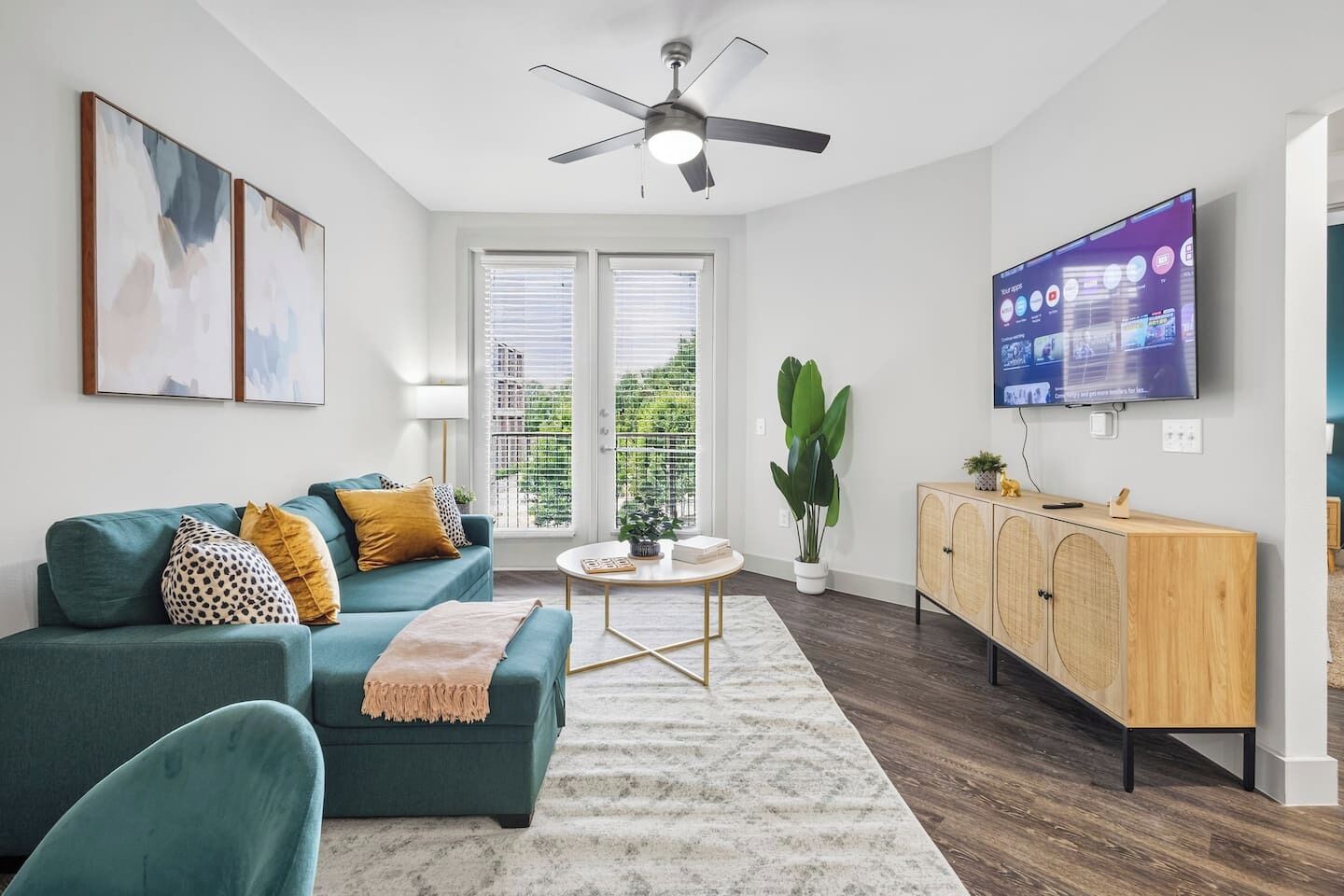 A living room with a teal sofa, a coffee table, a TV, and a wooden cabinet.