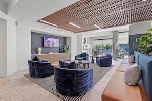 A modern interior with seating, a flat-screen TV, and a ceiling with wooden slats. - Luxury 1BR | Midtown Dallas | Pool, Gym, Free Parking (Dallas)
