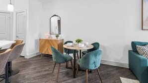 Uma sala de jantar moderna com uma mesa redonda, cadeiras cor turquesa e um armário de madeira.