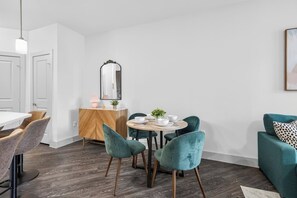 Ein stilvoller Essbereich mit einem runden Tisch, blaugrünen Stühlen und einer Holzkommode.