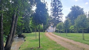 A gravel path leading to a building surrounded by trees and a small water body. - Brives-Ch Mill, Indianapolis (Courdemanche)