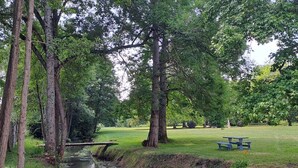 A park with a small stream, trees, and picnic tables. - Brives-Ch Tertre-Rouge Mill (Courdemanche)