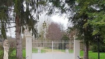 Ein verschlossenes Tor mit einem Kiesweg, der zu einem weißen Zaun führt.