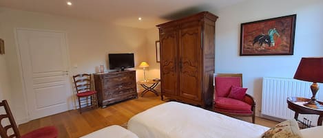 A room with a bed, a desk with a computer, a chair, a wardrobe, and a painting on the wall.