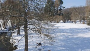 A snowy landscape with trees, a bench, and a table.