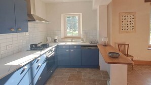 A kitchen with blue cabinets, a stove, and a window.