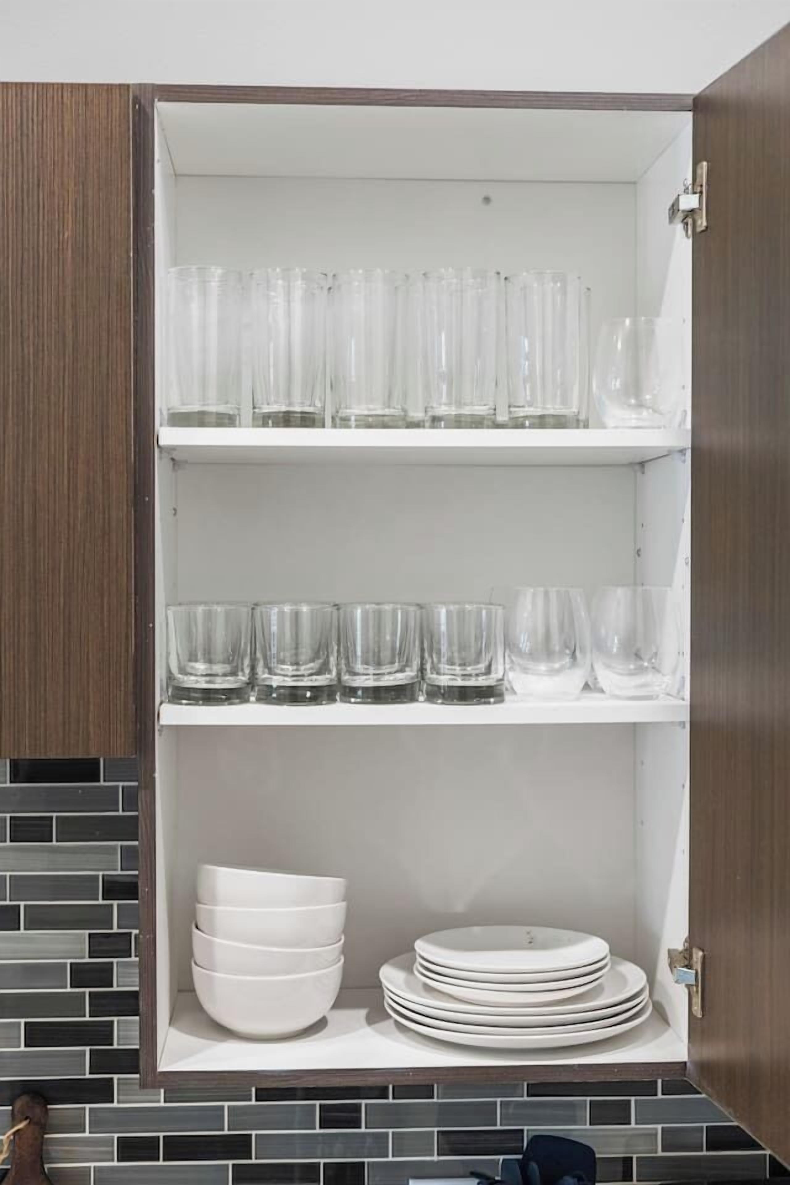 A kitchen cabinet with shelves holding glassware and bowls.