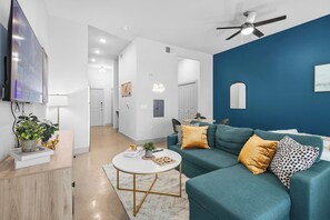 Una sala de estar moderna con un sofá azul turquesa, una mesa de centro y un televisor montado en la pared.