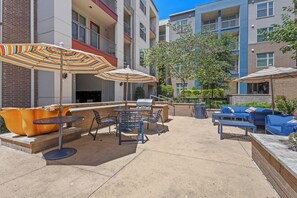An outdoor patio area with seating, a barbecue grill, and umbrellas. - Cozy Lux 1BR 1BA in Dallas | Mins to DT | Free Parking (Dallas)