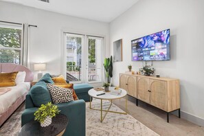 Ein modernes Wohnzimmer mit Bett, Sofa, Fernseher und Schrank.