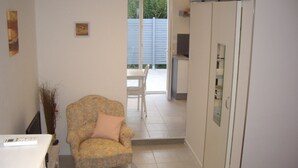 A room with a floral-patterned armchair, a white cabinet, and a sliding door leading to a balcony. - A LITTLE CORNER OF THE GARD PROVENCAL (Saint-Gilles)