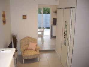 Ein Zimmer mit einem blumigen Sessel, einem weißen Schrank und einer Schiebetür, die auf einen Balkon führt.