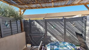 A covered patio with a table and chairs, a pergola overhead, and a fence with butterfly decorations. - A LITTLE CORNER OF THE GARD PROVENCAL (Saint-Gilles)