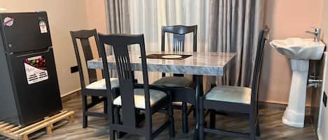 A dining area with a table and chairs, a refrigerator, and a sink.