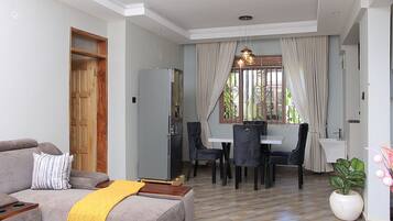 A living room with a sofa, a yellow throw, and a dining area with chairs and a table.