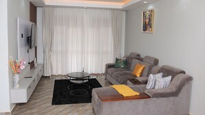 A modern living room with a sofa, a coffee table, and a TV. - Perfect 2-bedroom apartment with AC in enjoyable Kampala (Kampala)