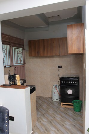 Une cuisine de taille réduite, avec des meubles de rangement en bois, une cuisinière à gaz et un petit réfrigérateur.