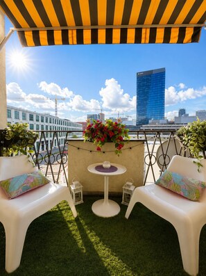 A rooftop terrace with two white chairs, a small round table, and a potted plant with red flowers. - Bright Central 2BR Business & City Stay - Nivy - Balcony - Fast WiFi (Bratislavský kraj)