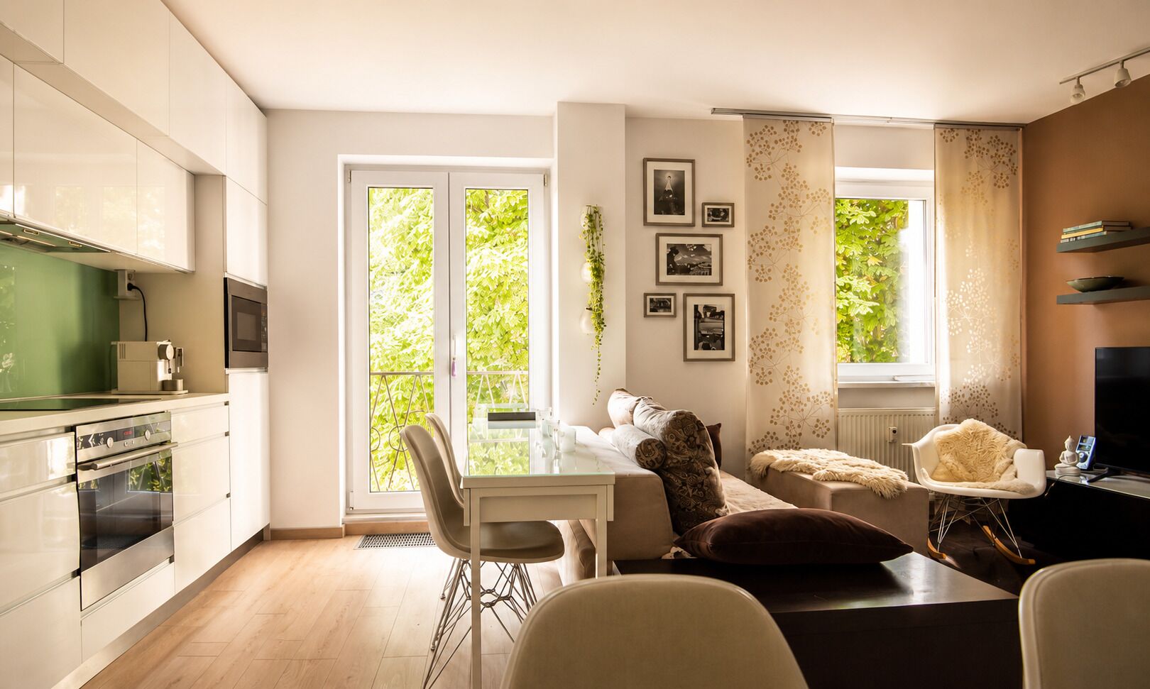 A modern kitchen with a dining area, a sofa, and a TV.